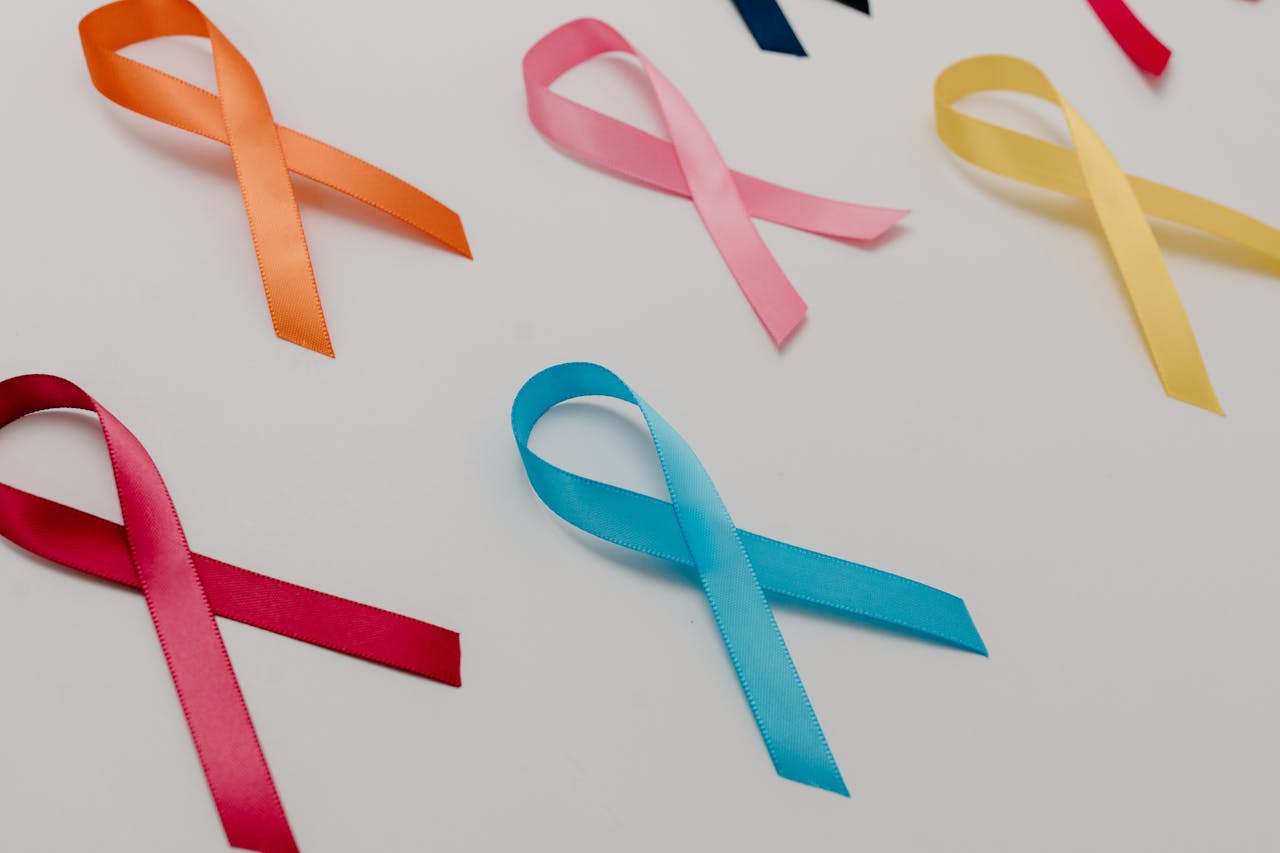 hero-img-01 Various colored ribbons representing different cancer awareness causes on a white surface.